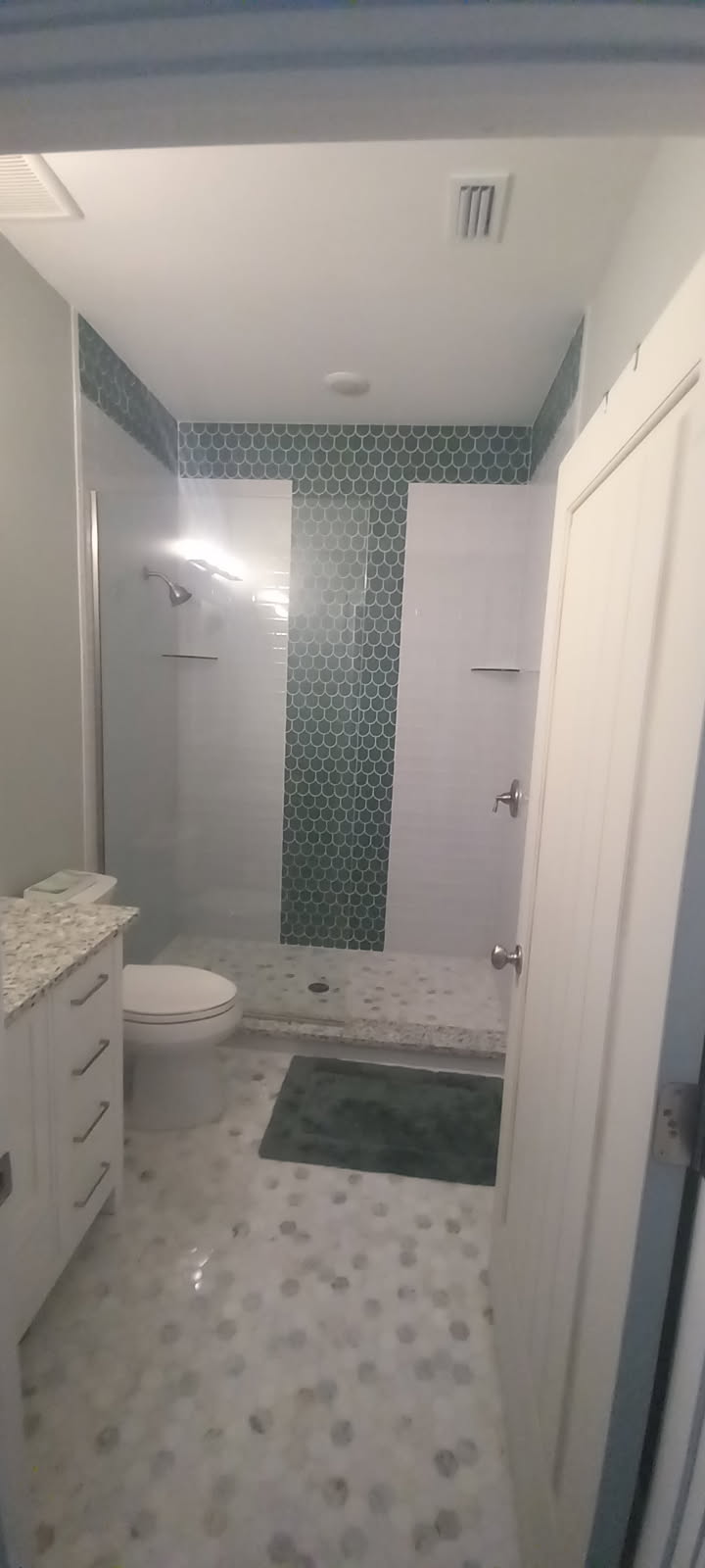 Bathroom remodel with teal hexagon tile and mosaic floor by Ultimate Design Remodelling